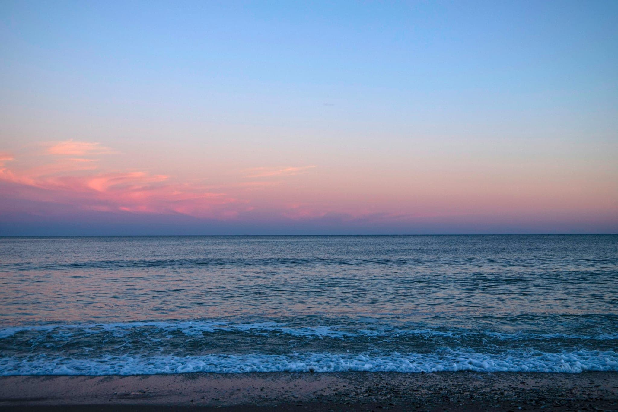 Calm evening sea with the horizon in the middle, in dark tones