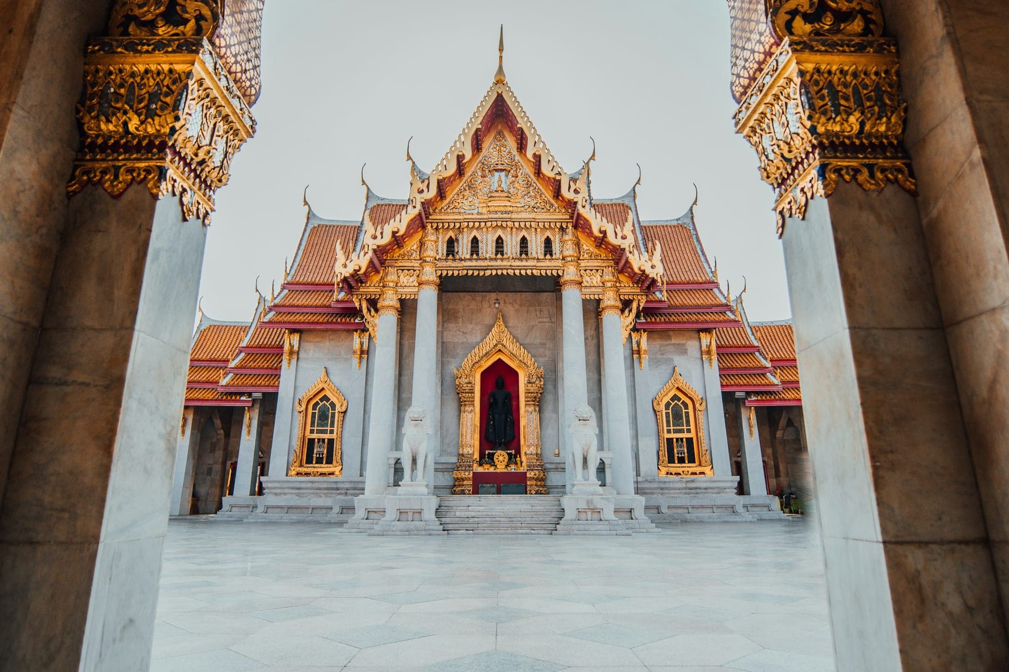 Wat Benchamabophit in Bangkok, the marble temple, seen between two marble columns in the morning light.