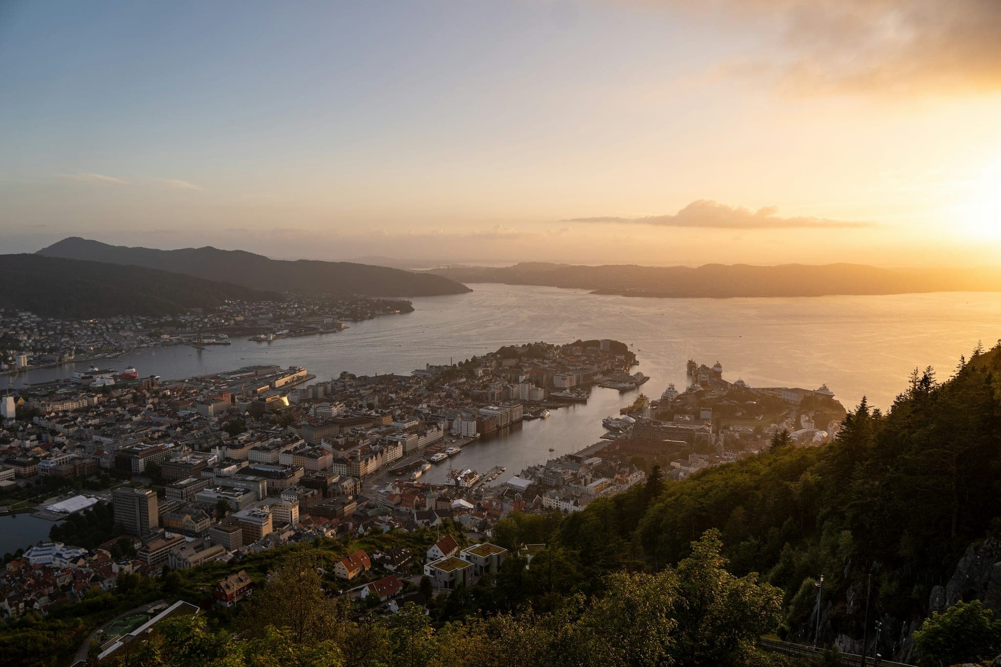 Bergen harbour at dusk: lit quays under dark mountains, with calm water in the foreground.