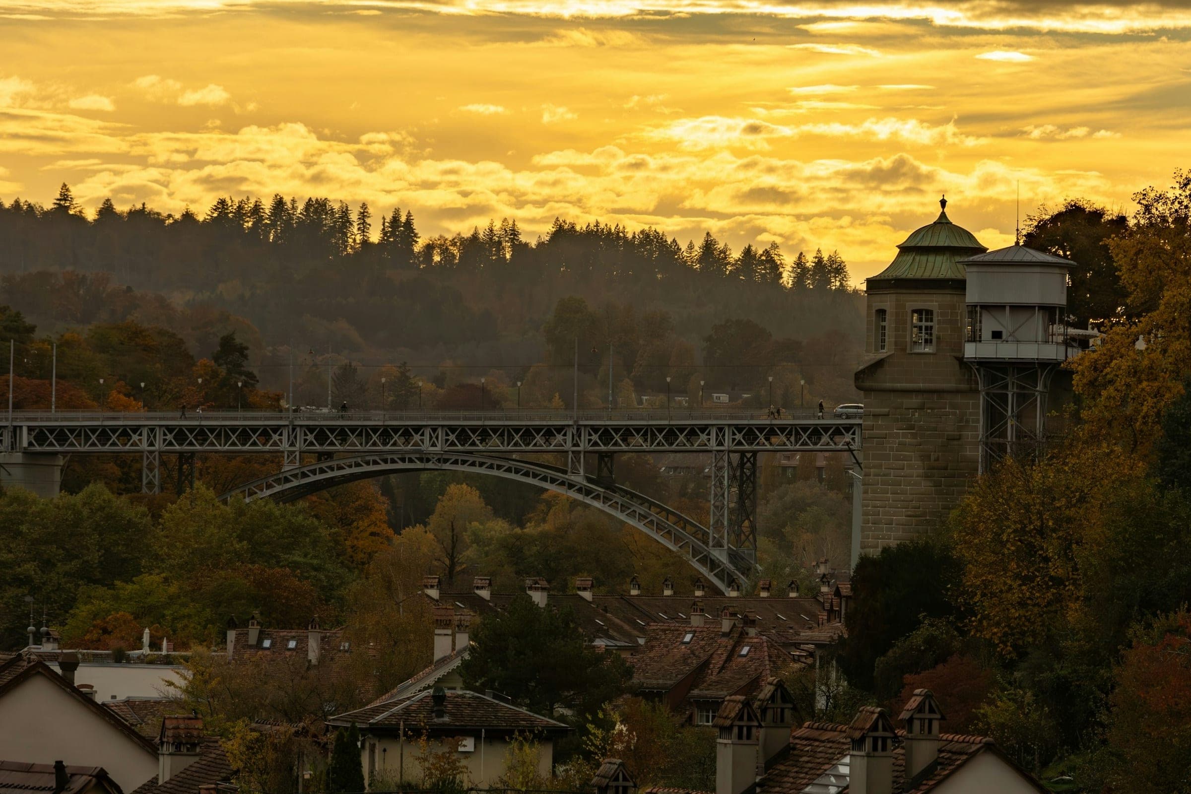 De Kirchenfeldbrücke boven de daken van de oude stad van Bern, bij gouden avondlicht.