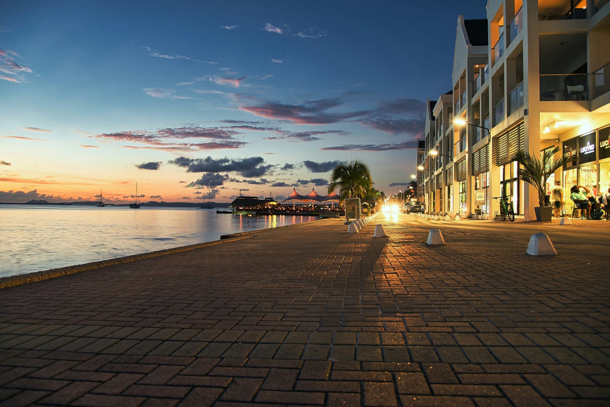 De boulevard van Kralendijk in het blauwe uur, met de verlichte gevels langs de kade en de Caribische Zee ernaast.
