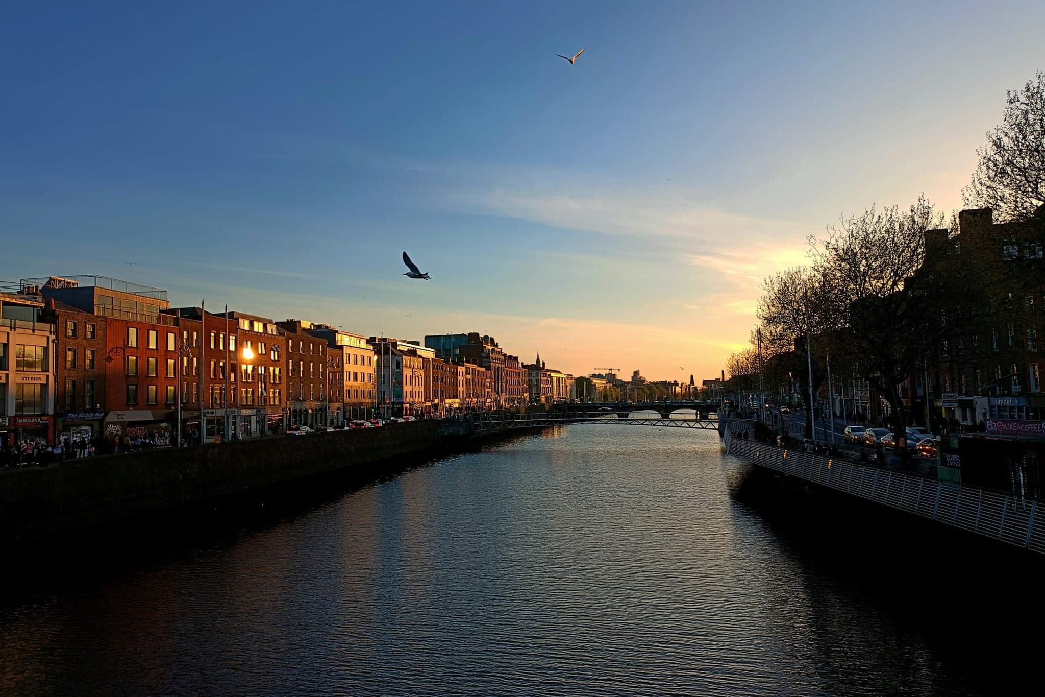 The Liffey in Dublin at dusk, with the quays on either side and a bridge in the distance.