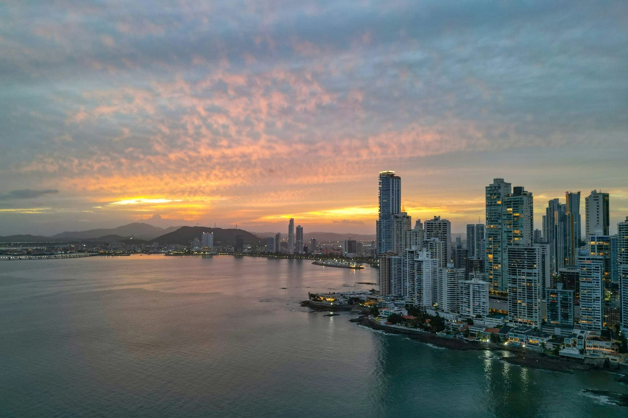 The skyline of Panama City at sunset across the bay, with a mackerel sky above the towers.