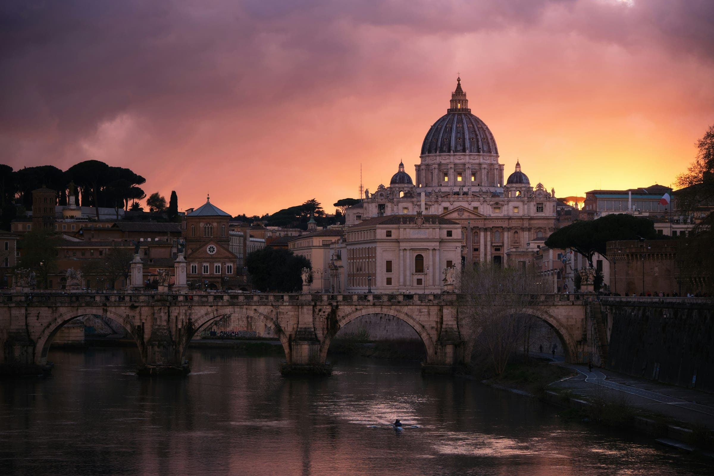 De Ponte Sant'Angelo over de Tiber in Rome, met de koepel van de Sint-Pietersbasiliek in het avondrood.