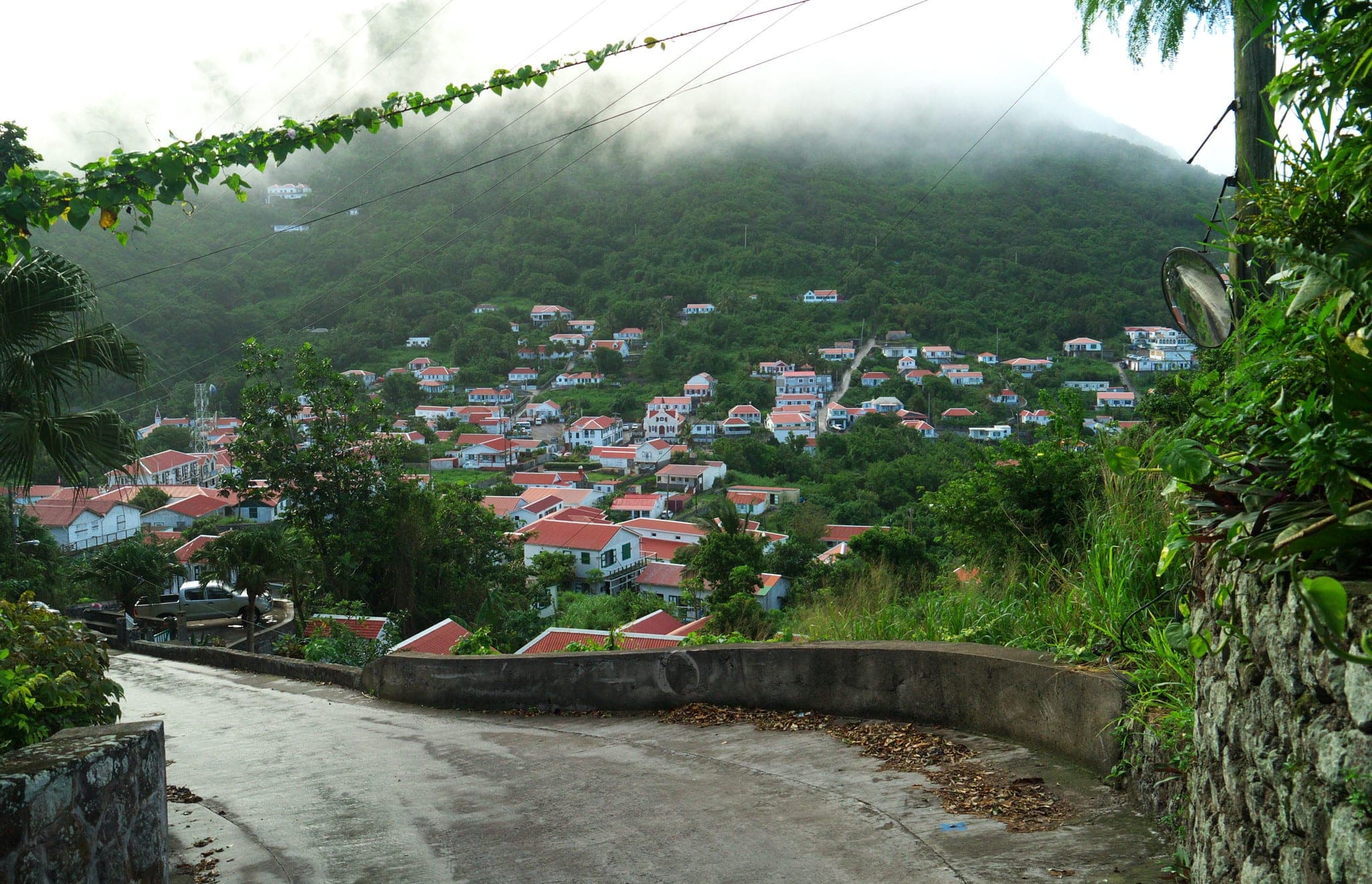 Red roofs and white cottages of Windwardside against the green slopes of Mount Scenery on Saba, under cumulus clouds.