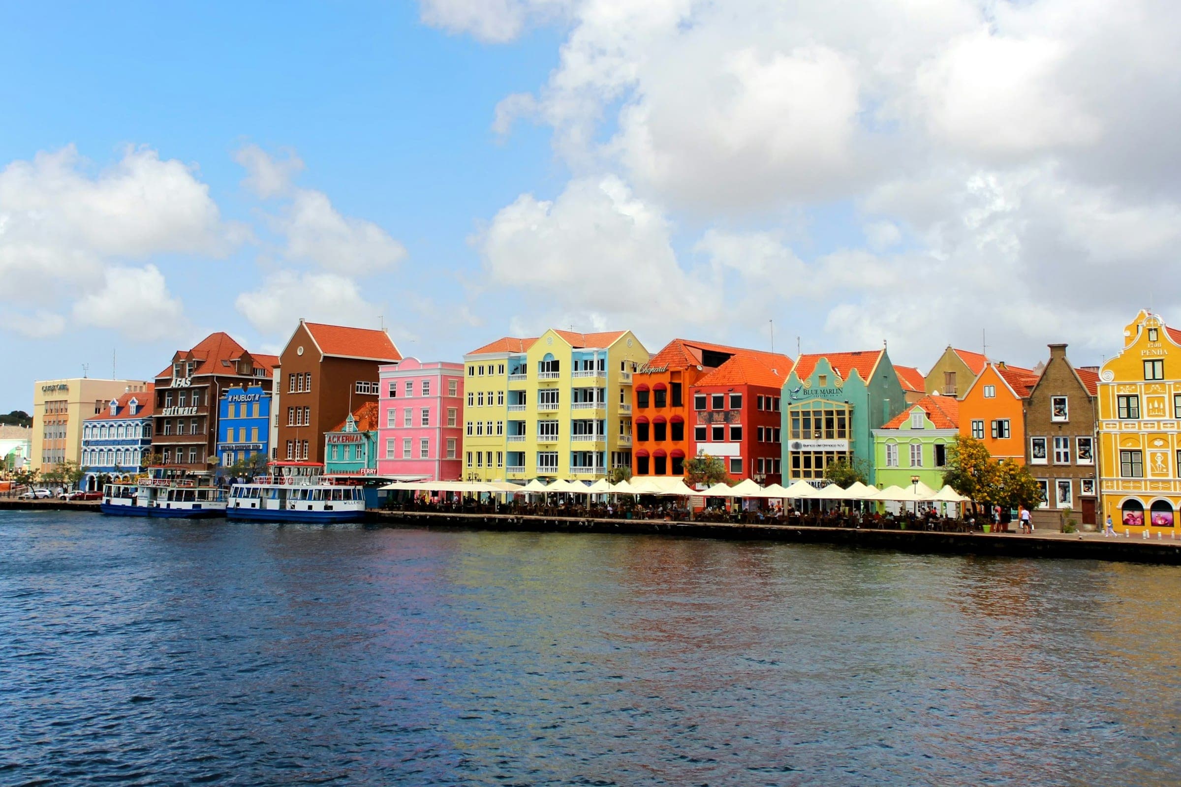 De gekleurde gevels van de Handelskade in Willemstad, gezien over het water van de Sint Annabaai.